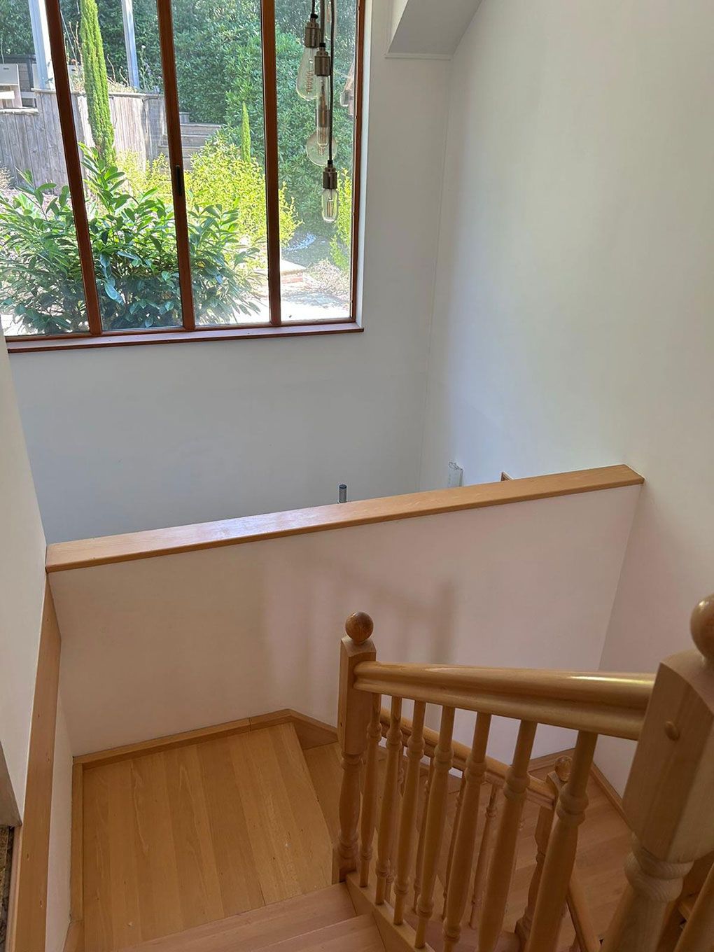 Oak staircase beneath a feature gable window in a finished home